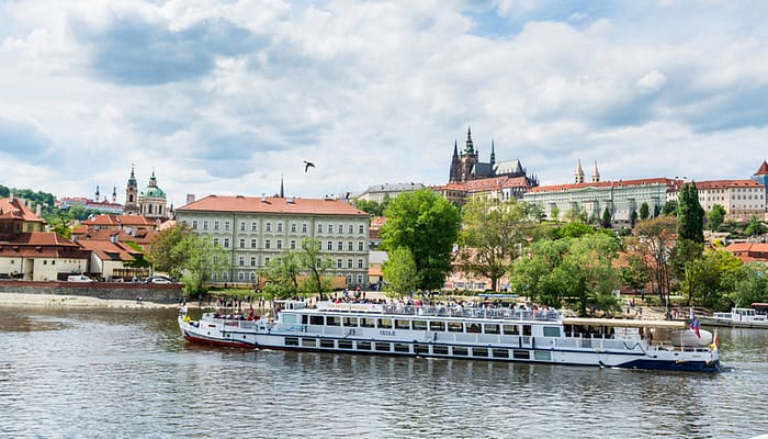 Cruise ship sailing on the Vltava River, with the background of Prague Castle, the world's largest one in the world.